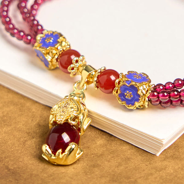 Garnet Pixiu Flower Bracelet – close-up of gold Pixiu pendant with red stone, blue enamel flower charms and red agate beads, feng shui wealth