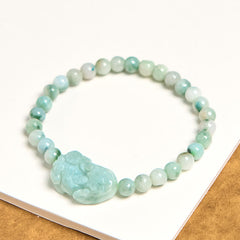 Natural Green Jade Pixiu Carved Luck Bead Bracelet – bracelet displayed on white book with natural wood edge, elegant jade accessory