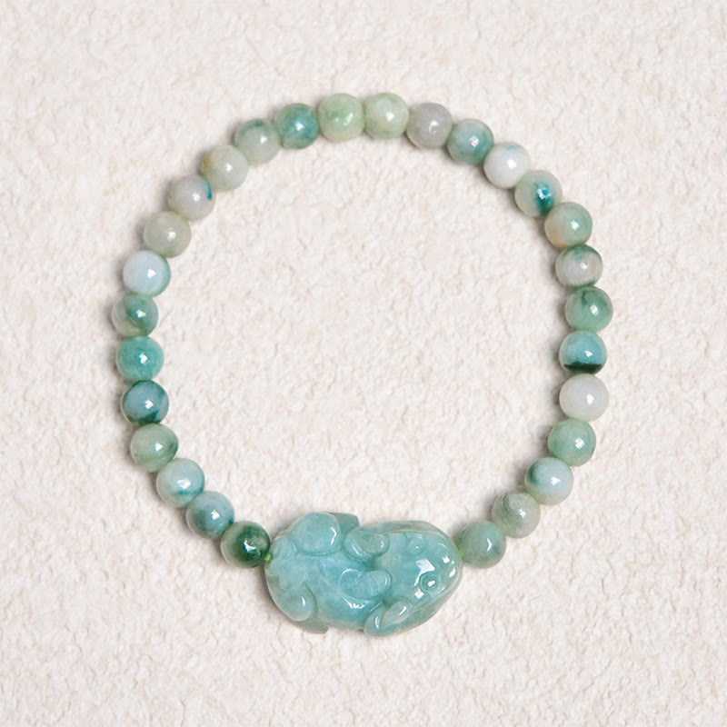 Natural Green Jade Pixiu Carved Luck Bead Bracelet – top-down view of green jade bead bracelet on textured white surface, feng shui bracelet