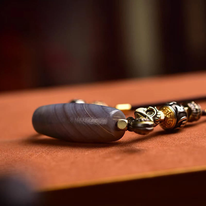 Tibetan Dzi Bead Agate Protection Pendant – low angle macro, banded agate stone with antique brass fittings, dzi bead