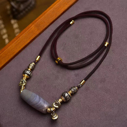 Tibetan Dzi Bead Agate Protection Pendant – full necklace laid flat on textured fabric, agate bead with metalwork, dzi bea...