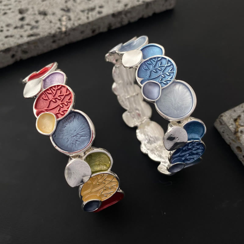 Tree of Life Alloy Elastic Bracelet – two multicolor bracelets on dark surface with stone props, angle view