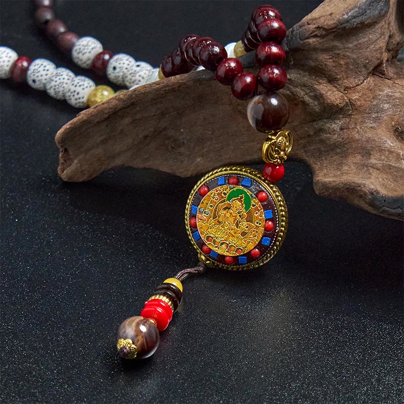 Tibetan Om Mani Padme Hum Necklace – Close-up cloisonné pendant with deity figure, driftwood prop, spiritual jewelry