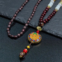 Tibetan Om Mani Padme Hum Necklace – Elevated angle on slate, mixed wood and red beads, enameled amulet