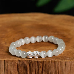 Cat's Eye 990 Sterling Silver Pixiu Positive Energy Bracelet – white cat's eye beads with silver Pixiu on natural wood surface, feng shui wealth bracelet