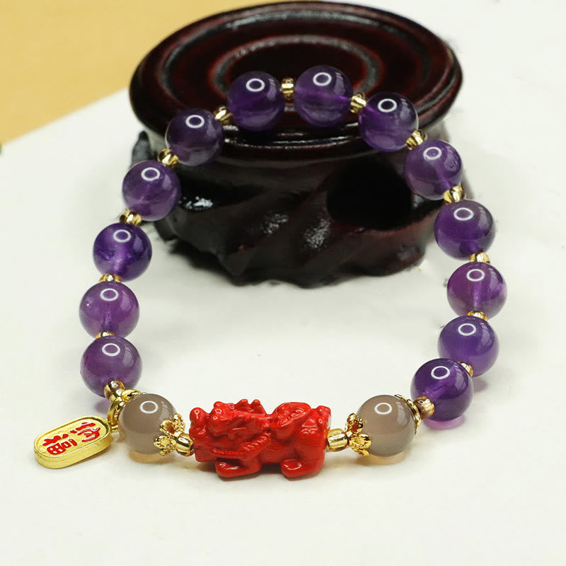 Amethyst Cinnabar Pi Xiu Fu Character Balance Bracelet – close-up on dark wood stand highlighting red cinnabar Pixiu detail, wealth luck charm