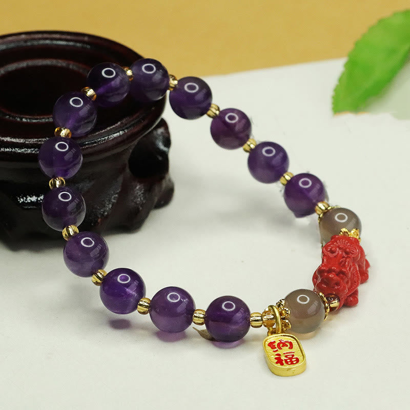 Amethyst Cinnabar Pi Xiu Fu Character Balance Bracelet – bracelet displayed on dark wooden stand with green leaf decor, spiritual balance accessory