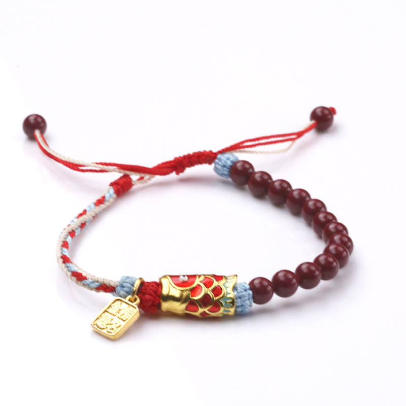 Cinnabar Koi Fish Blessing Bracelet – three-quarter on white, burgundy beads, gold fish charm, woven cord, adjustable
