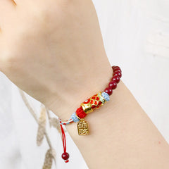 Cinnabar Koi Fish Blessing Bracelet – on wrist with white background, gold koi charm, success pendant, red blue woven cord