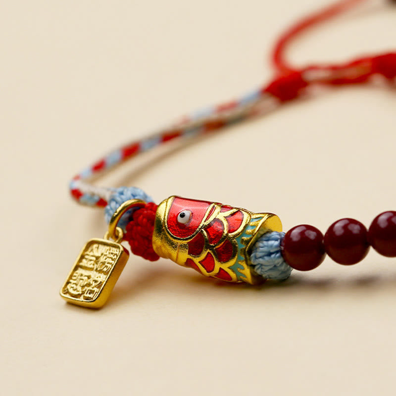 Cinnabar Koi Fish Blessing Bracelet – macro close-up side angle, gold koi charm, cinnabar beads, tri-color cord, cream bg