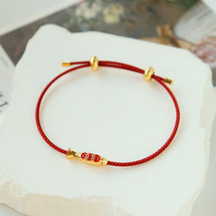 Brass Koi Fish Red String Bracelet – on white stone surface, gold koi charm red enamel scales, adjustable prosperity cord