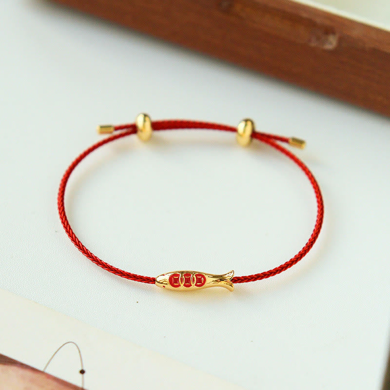 Brass Koi Fish Red String Bracelet – on cream surface, wooden frame, gold koi charm detail, adjustable red string bracelet