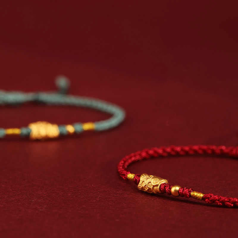 999 Gold Koi Fish Red String Bracelet – macro diagonal close-up, gold koi in sharp focus, teal blurred