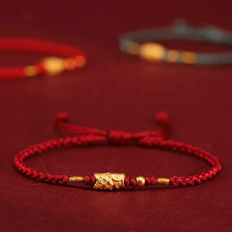 999 Gold Koi Fish Red String Bracelet – red cord with gold koi charm and beads, side view on burgundy, luck