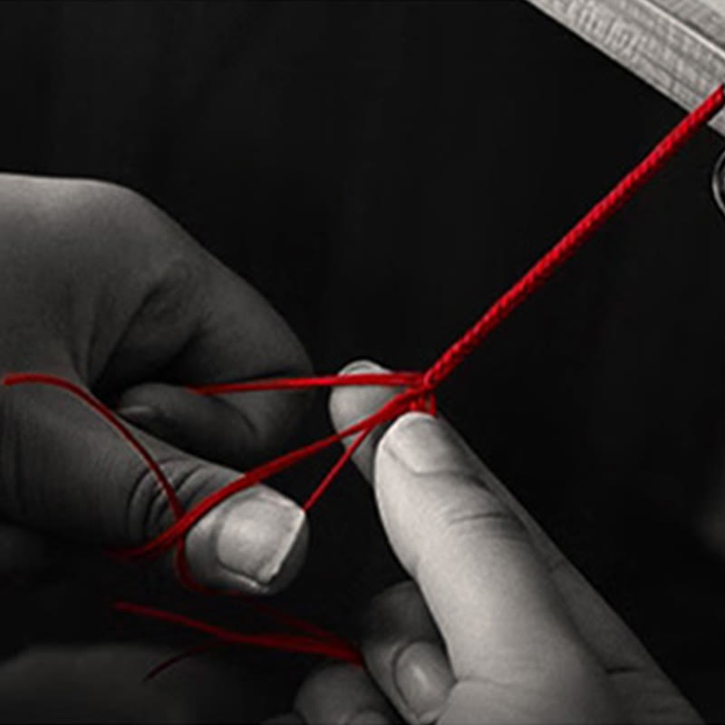 999 Gold Koi Fish Red String Bracelet – close-up hands knotting red string, B&W with red cord, handmade