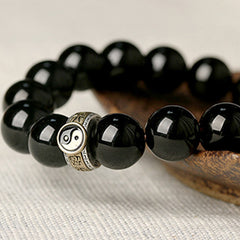 Black Obsidian Nine-Character Mantra Yin Yang Bracelet - low-angle yin-yang charm macro, polished stone beads