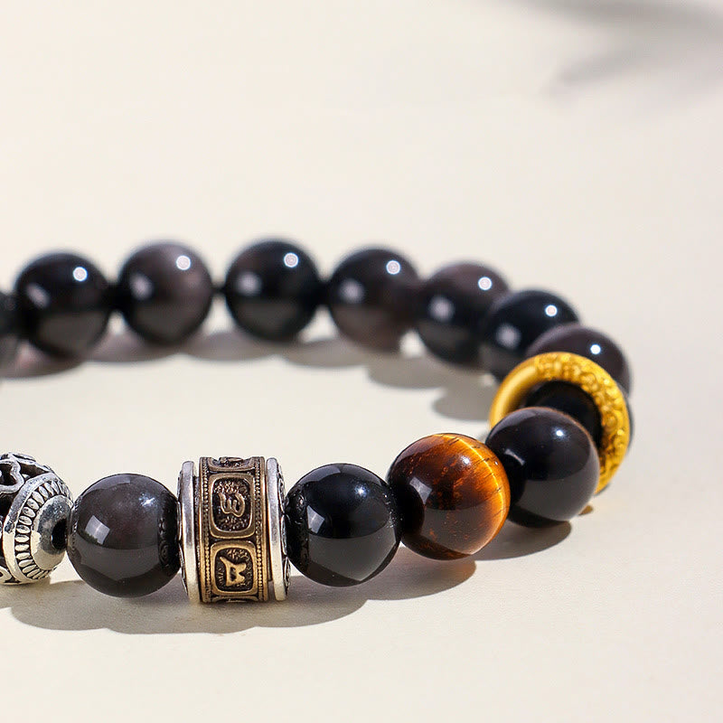 Silver Sheen Obsidian Tiger Eye Bracelet – low angle close-up of engraved barrel bead with gold inlay Sanskrit symbols and tiger eye focal point, grounding bracelet