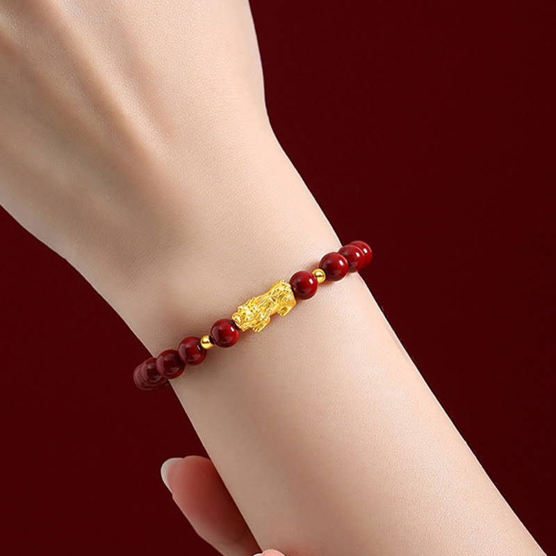 999 Gold Cinnabar PiXiu bracelet – worn on female wrist dark red background, gold cinnabar feng shui