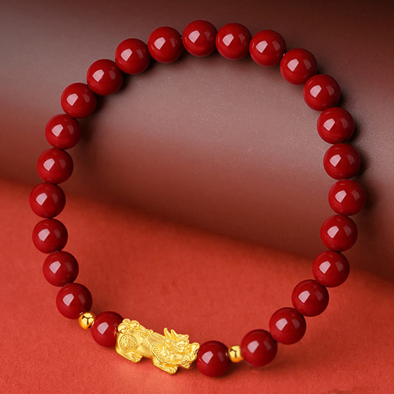 999 Gold Cinnabar PiXiu bracelet – red cinnabar beads with gold PiXiu on brown surface, wealth protection