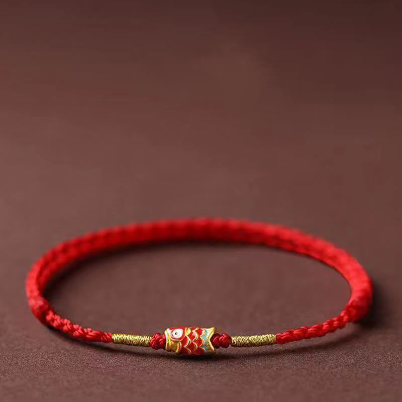 Koi Fish Braided Red String Bracelet – gold koi charm with red-orange scales, low side angle, brown bg