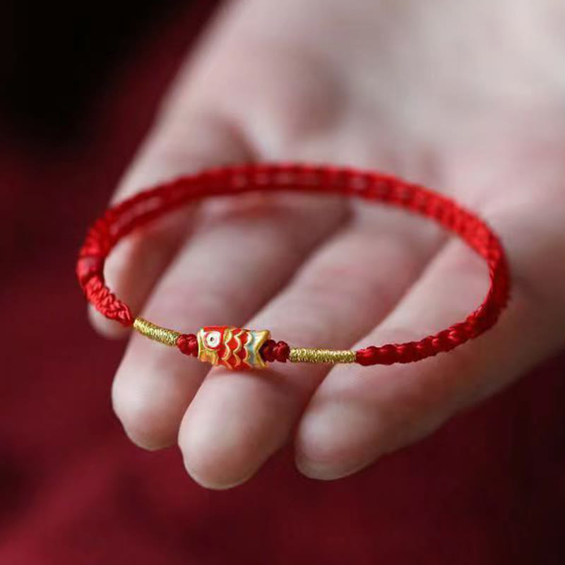 Koi Fish Braided Red String Bracelet – barrel koi charm on red cord resting on hand, burgundy bg, macro