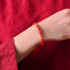 Handcrafted Cinnabar PiXiu bracelet – red cord worn on wrist, cinnabar PiXiu charm closeup, wealth