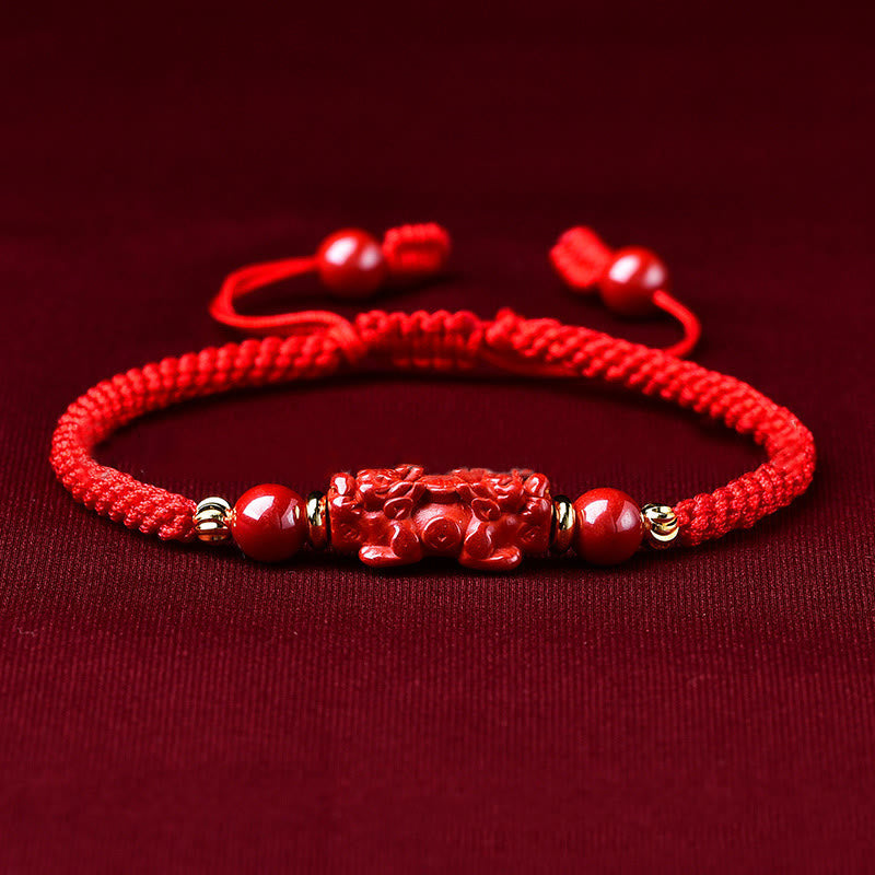 Handcrafted Cinnabar PiXiu bracelet – red braided cord with cinnabar PiXiu on dark fabric, feng shui