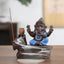 Ganesh Backflow Incense Burner - Seated deity in terracotta with blue garments, smoke cascading down, protection symbol