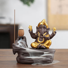 Ganesh Backflow Incense Burner - Gold-accented dark ceramic Ganesha, flowing smoke cascade, elephant deity