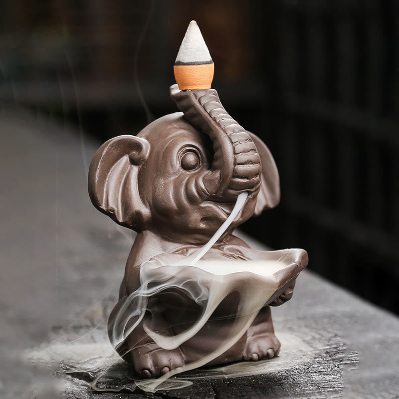 Elephant Backflow Incense Burner - Side view with cascading smoke on dark stone, purple clay censer