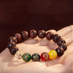 Five Directions Wealth Bracelet - Five-element wealth bracelet resting on hand, carved wood with gemstone focal beads