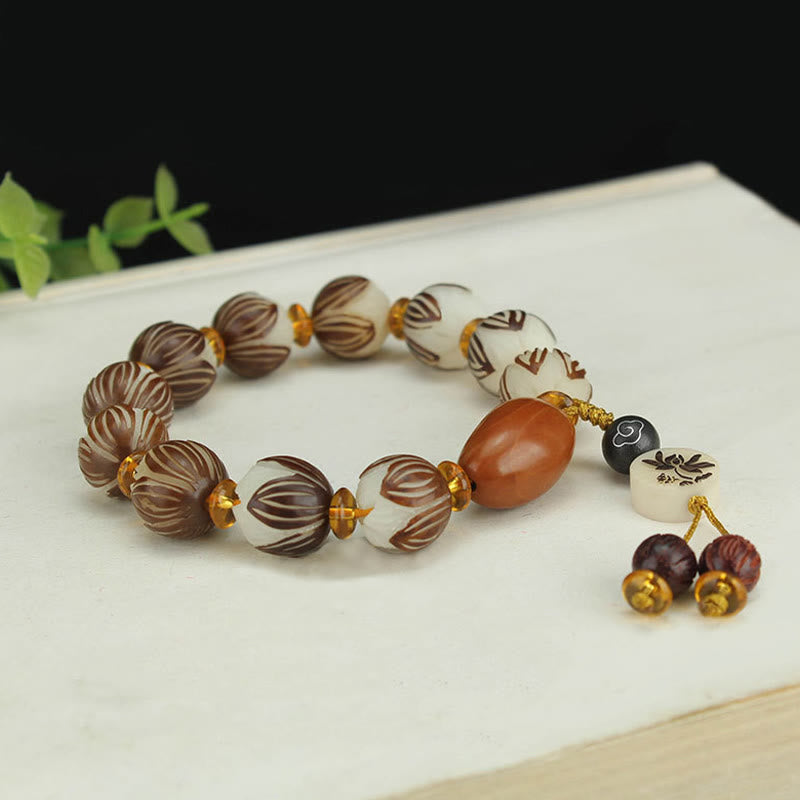 Tibetan Mala Bodhi Seed Lotus Bracelet - on book prop, lotus bead carving, warm tones