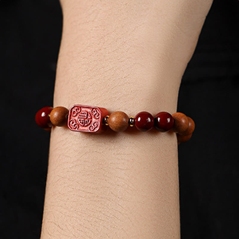 Cinnabar Wood Lotus Fu Bracelet - on wrist side view, Fu charm focal, black backdrop