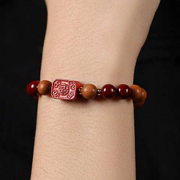 Cinnabar Wood Lotus Fu Bracelet - on wrist side view, Fu charm focal, black backdrop