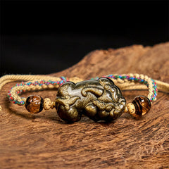 Gold Sheen Obsidian PiXiu bracelet – rope bracelet on wooden surface front view, protection good luck