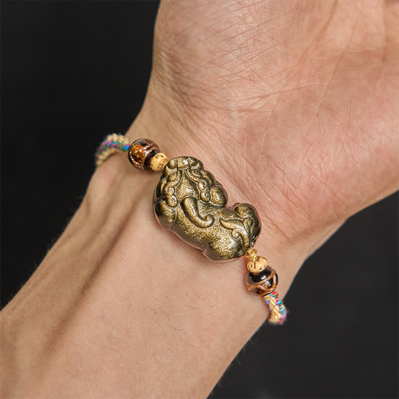 Gold Sheen Obsidian PiXiu bracelet – PiXiu charm closeup on wrist, black background gold detail