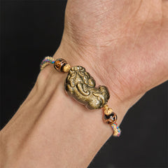 Gold Sheen Obsidian PiXiu bracelet – PiXiu charm closeup on wrist, black background gold detail