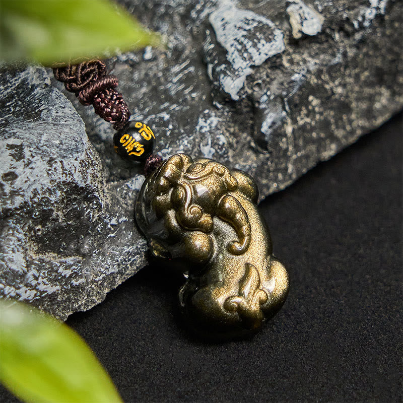 Gold Sheen Obsidian PiXiu Wealth Rope Necklace Pendant – pendant on dark rock with green leaf, maroon rope feng shui wealth