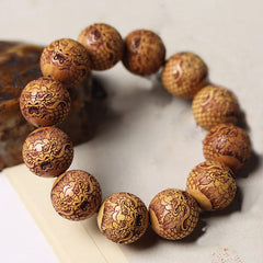 Sandalwood Dragon Bracelet – carved foo dog beads at angled overhead view, Calm