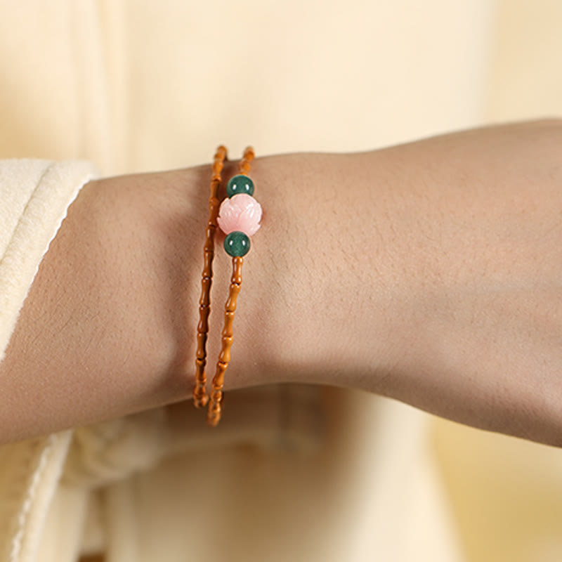 Olive Pit Lotus Double Circle Bracelet – double-wrap worn on wrist with cream fabric sleeve and dark bokeh, Inner Strength