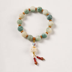 Bodhi Seed Zakiram Bracelet - White flat lay displaying carved lion charm with red tassel, ethnic bead bracelet