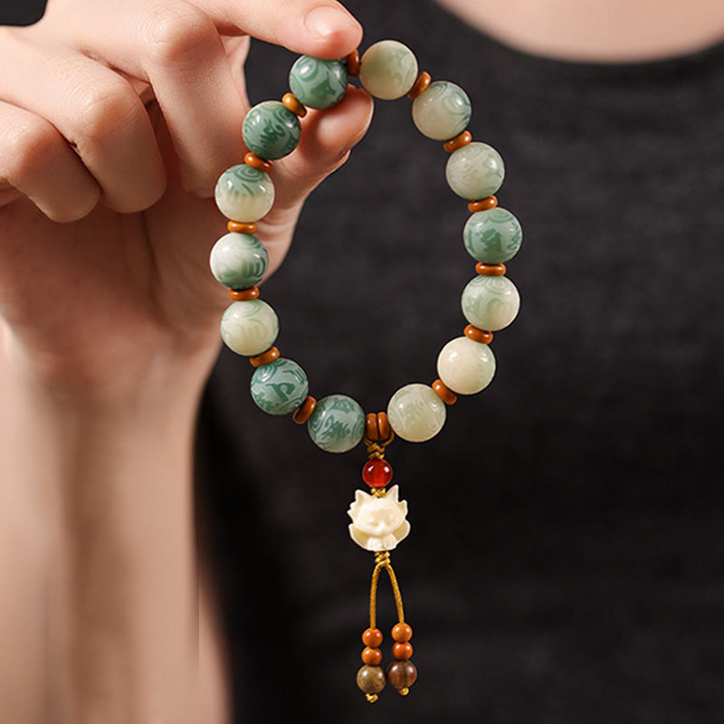 Bodhi Seed Zakiram Bracelet - Hand-held close-up showing carved fox pendant and marbled bead details, spiritual wrist jewelry