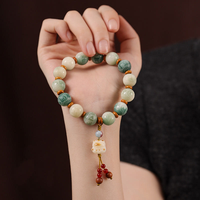 Bodhi Seed Zakiram Bracelet - Hand-held lifestyle shot displaying carved foo dog pendant and earth tone beads, Zen jewelry