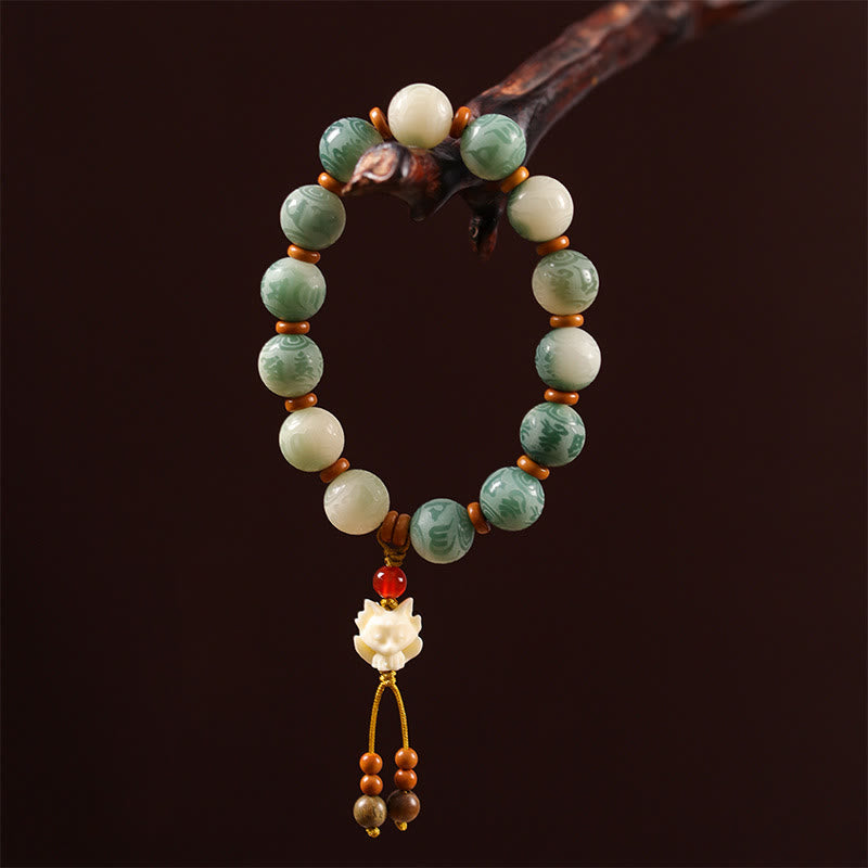 Bodhi Seed Zakiram Bracelet - Hanging from wood branch with carved lotus pendant, dark background, prayer jewelry