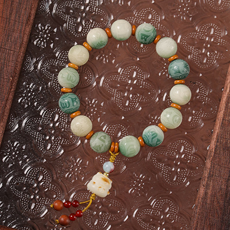 Bodhi Seed Zakiram Bracelet - Resting on carved dark lacquer tray showing lotus-carved green beads, artisan bead bracelet