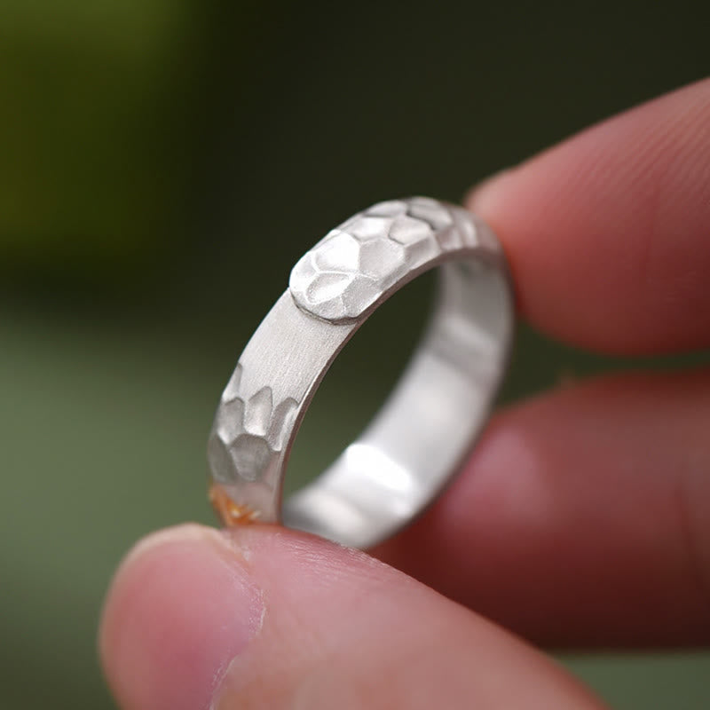 Hammered Om Mani Padme Hum Ring - held between fingers showing hammered finish, artisan silver band