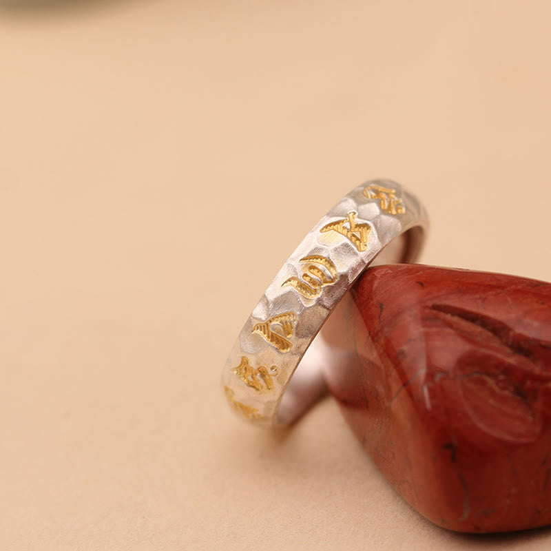 Hammered Om Mani Padme Hum Ring - resting on natural stone prop, gold spiritual script detail