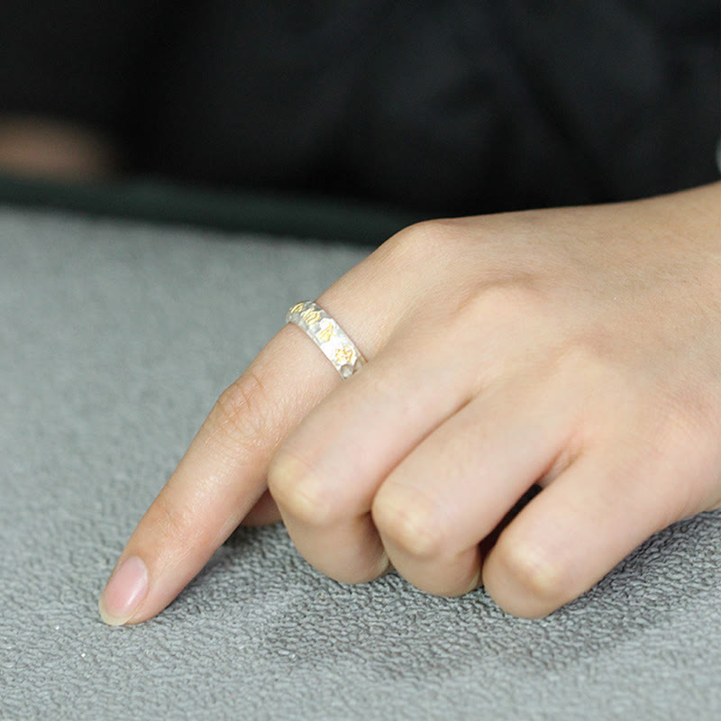 Hammered Om Mani Padme Hum Ring - lifestyle hand shot on gray fabric, textured gold silver band