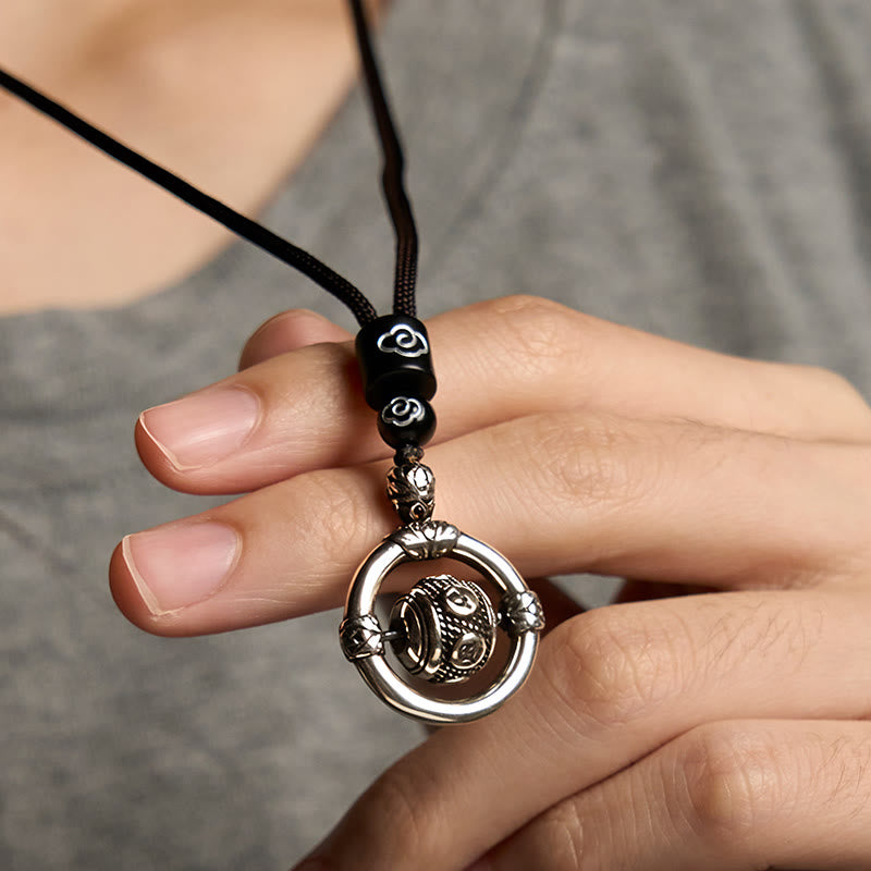 Om Mani Padme Hum Pendant – Lifestyle close-up of rotating mechanism held against gray fabric, mindfulness jewelry