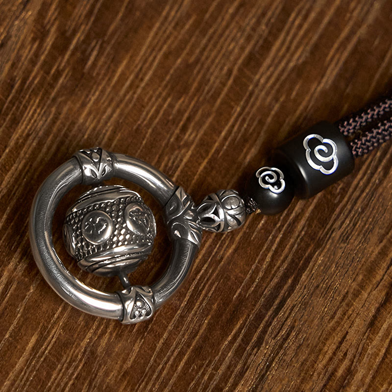 Om Mani Padme Hum Pendant – Overhead angle on wood grain highlighting silver ring and rotating sphere, meditation pendant